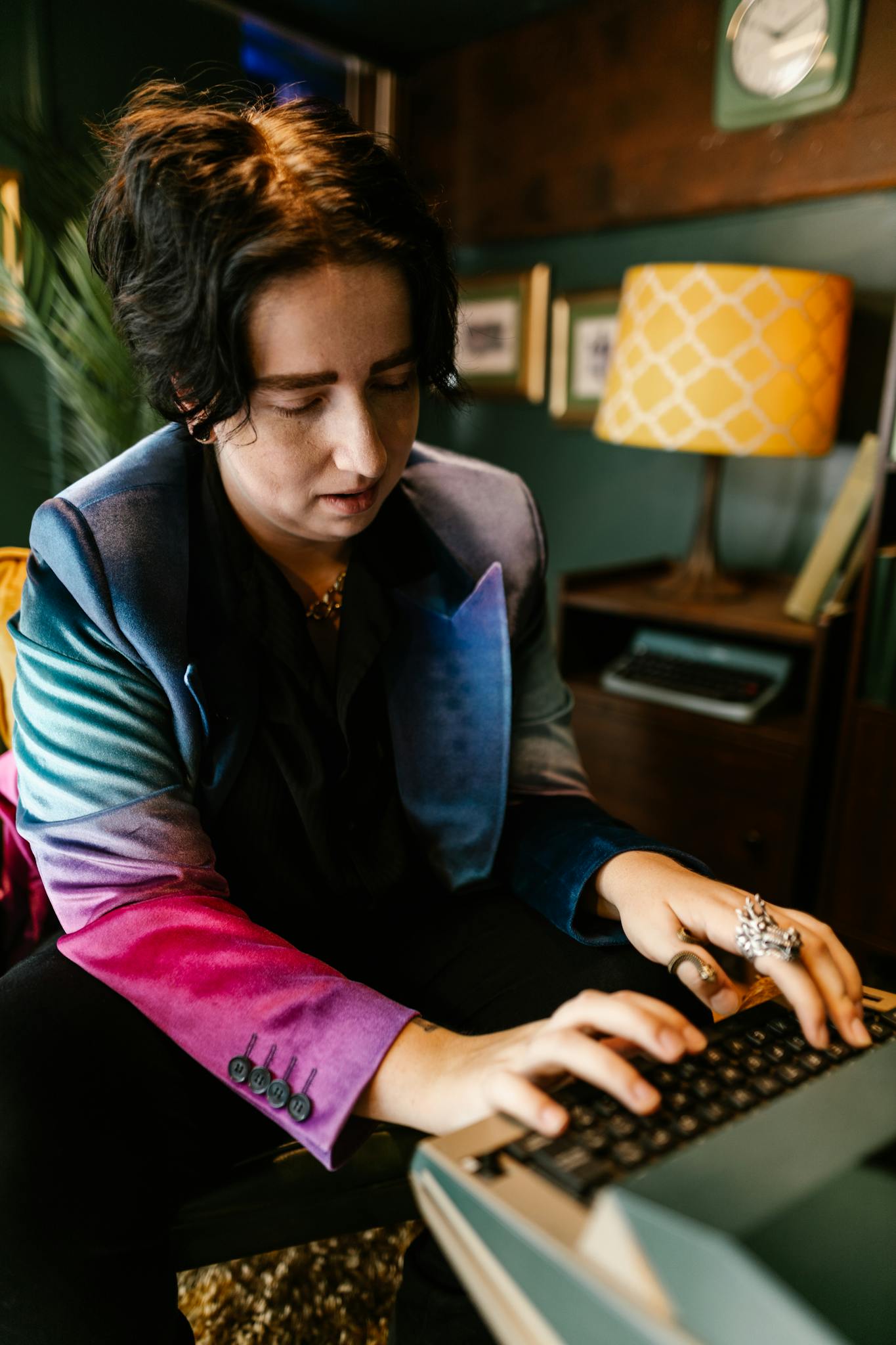 Person with unique style typing on a vintage typewriter in a cozy room.